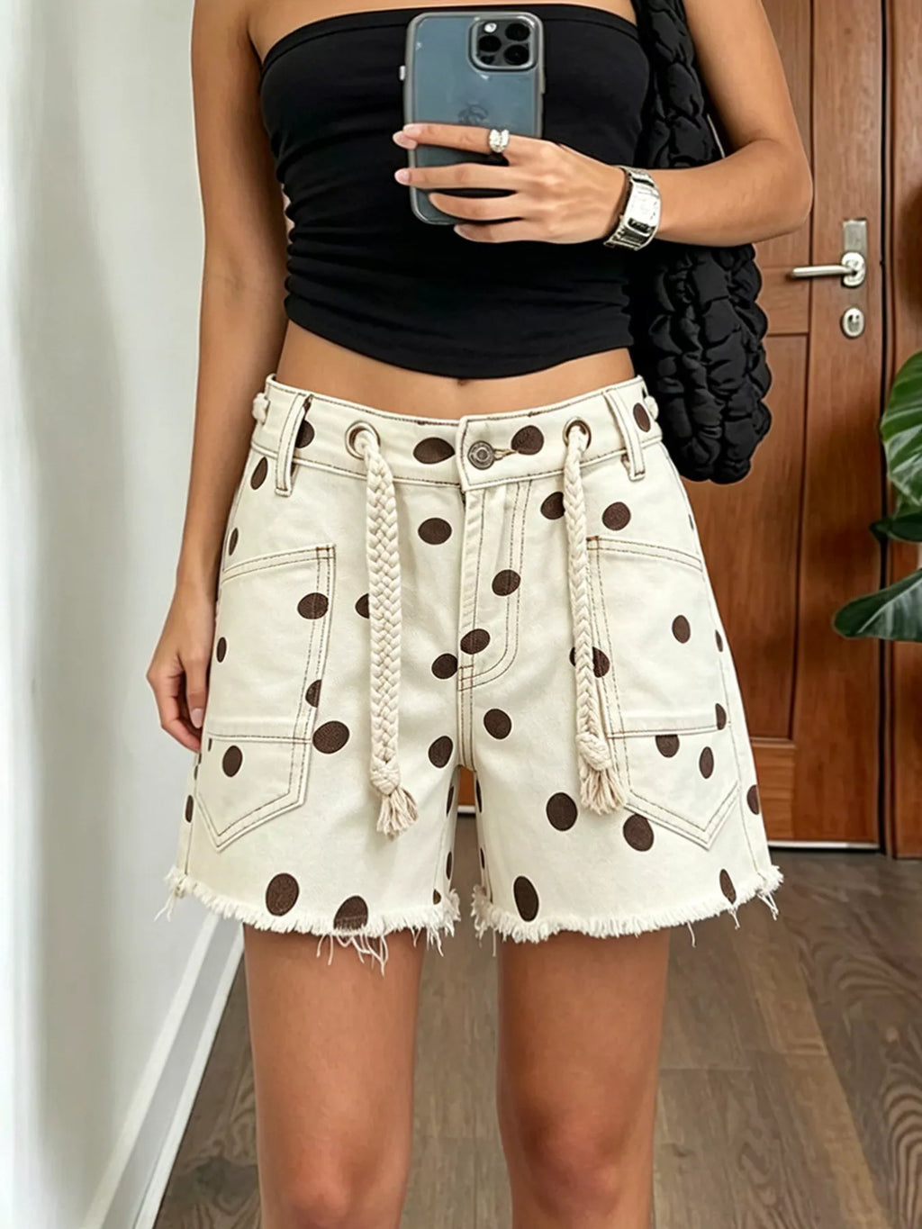 Polka dot denim shorts with braided drawstring, featuring raw hem and pockets, in chocolate color.