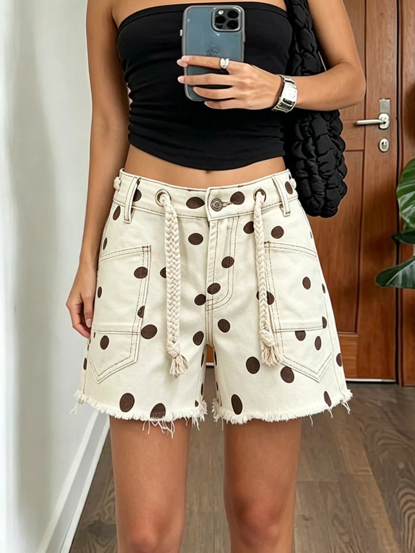 Polka dot denim shorts with braided drawstring, featuring raw hem and pockets, in chocolate color.