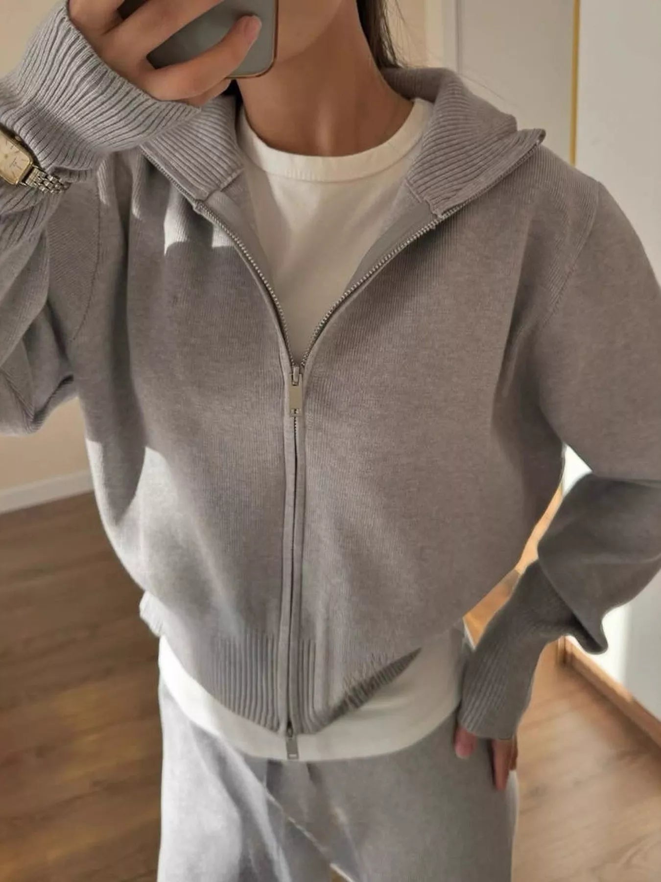 Close-up of a model wearing a plush zip-up hoodie and pants set in dark gray, showcasing the stylish design and cozy fabric.