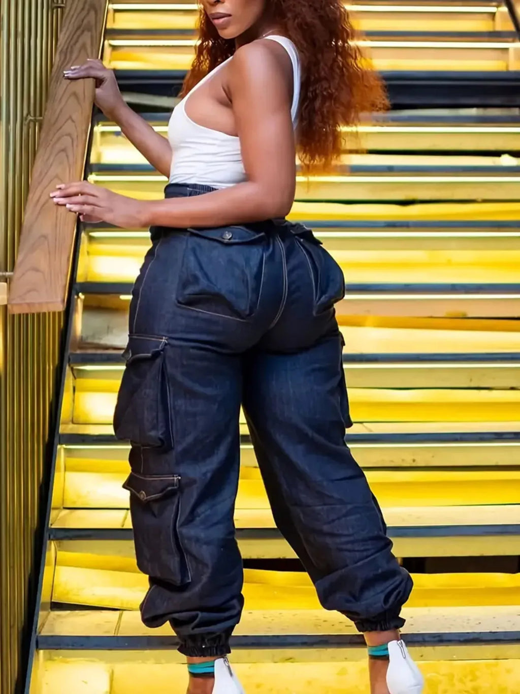 Model showcasing fashionable plus size jeans in high-waisted cargo style on stylish staircase.