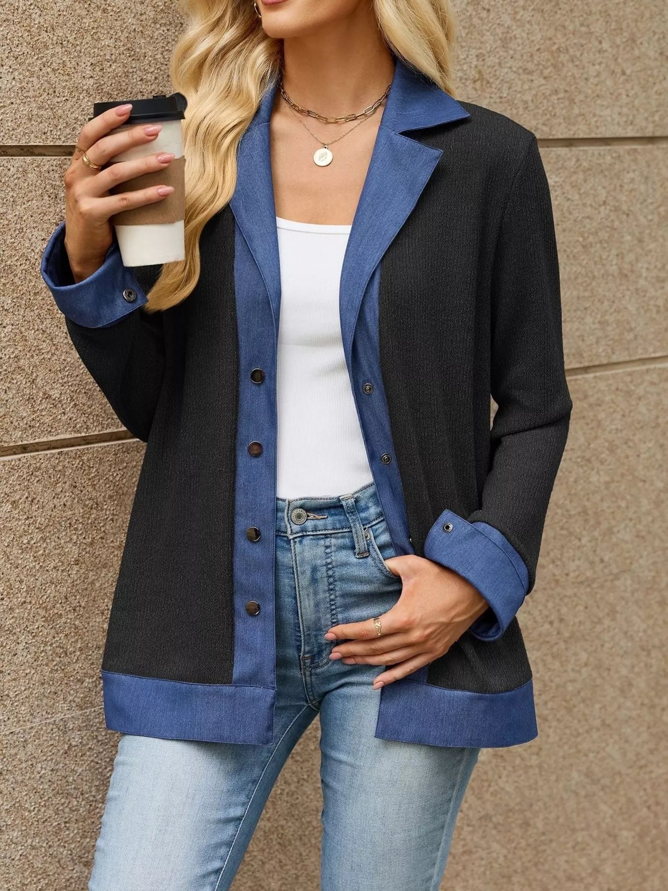 Woman wearing contrast denim lapel jacket holding coffee, showcasing the stylish blend of blue and black fabric.