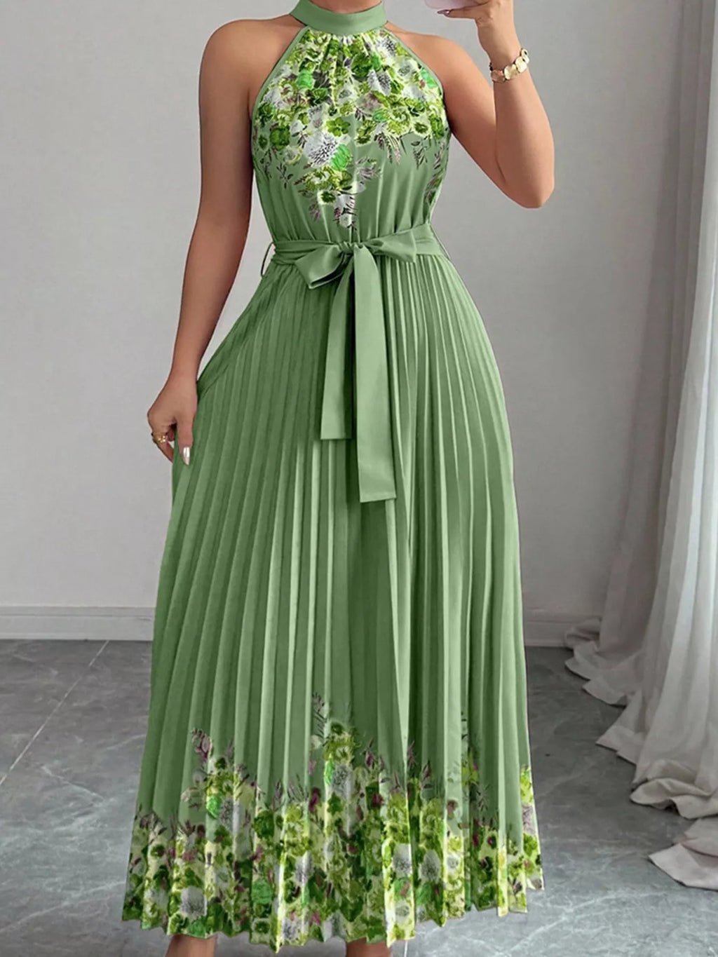 Summer maxi dress with halter neck and floral print, featuring pleats and a flattering silhouette in green.