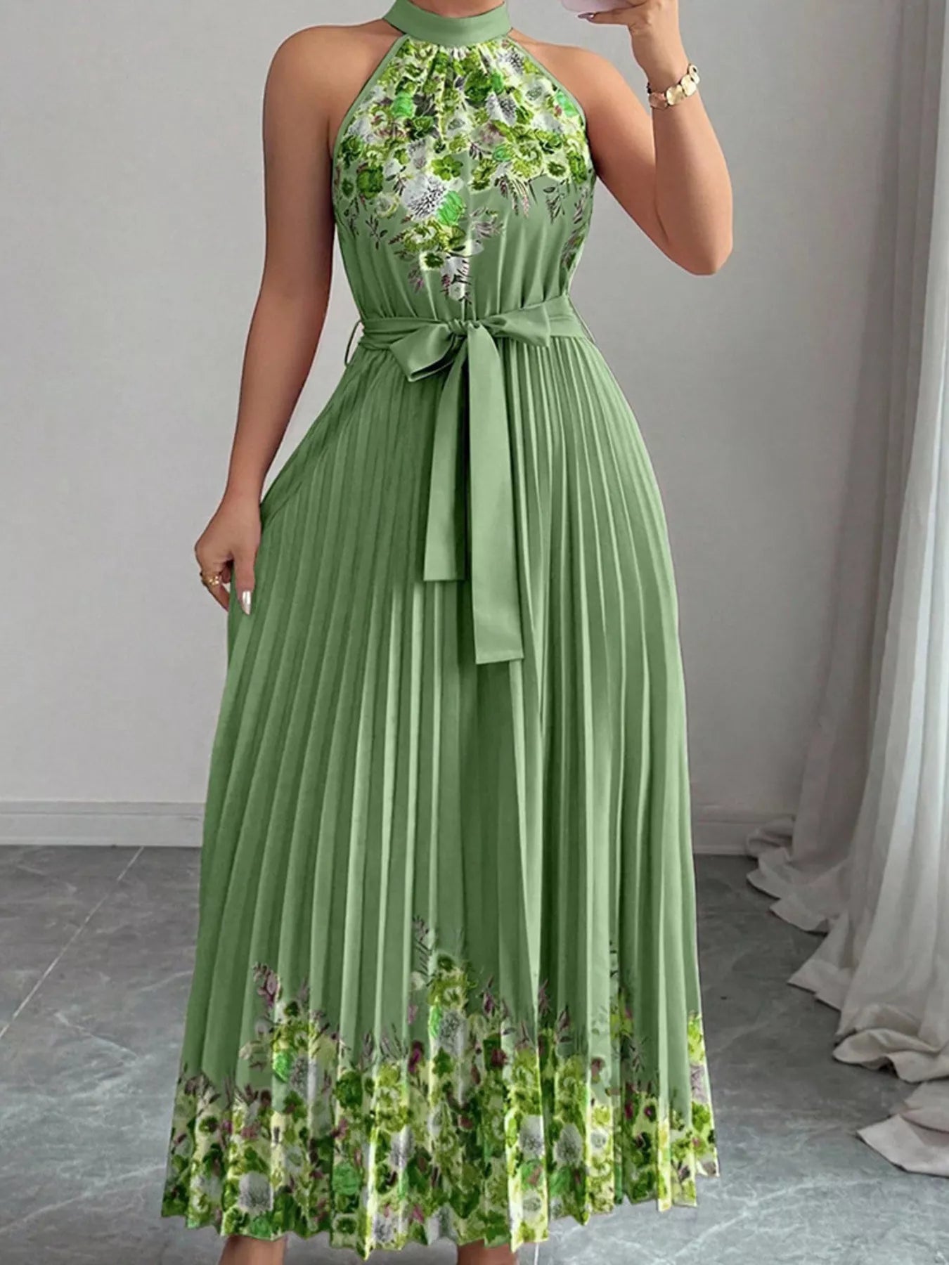 Summer maxi dress with halter neck and floral print, featuring pleats and a flattering silhouette in green.