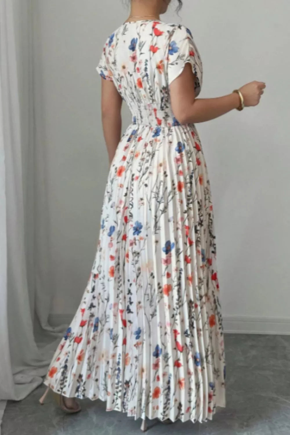 Back view of a floral dress for women, featuring pleated design and vibrant floral print, perfect for elegant occasions.