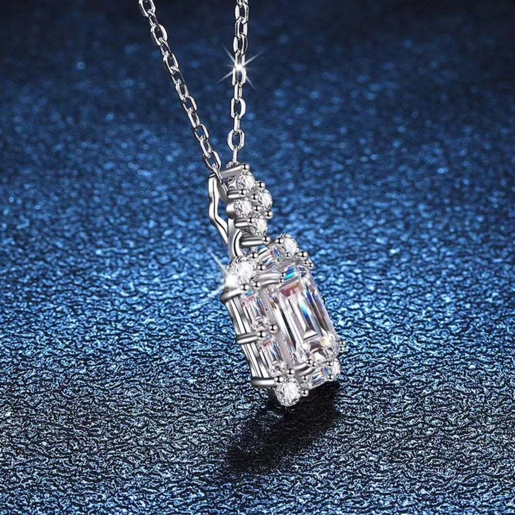 Moissanite jewelry 1 Carat 925 Sterling Silver Pendant Necklace on a shimmering blue background.