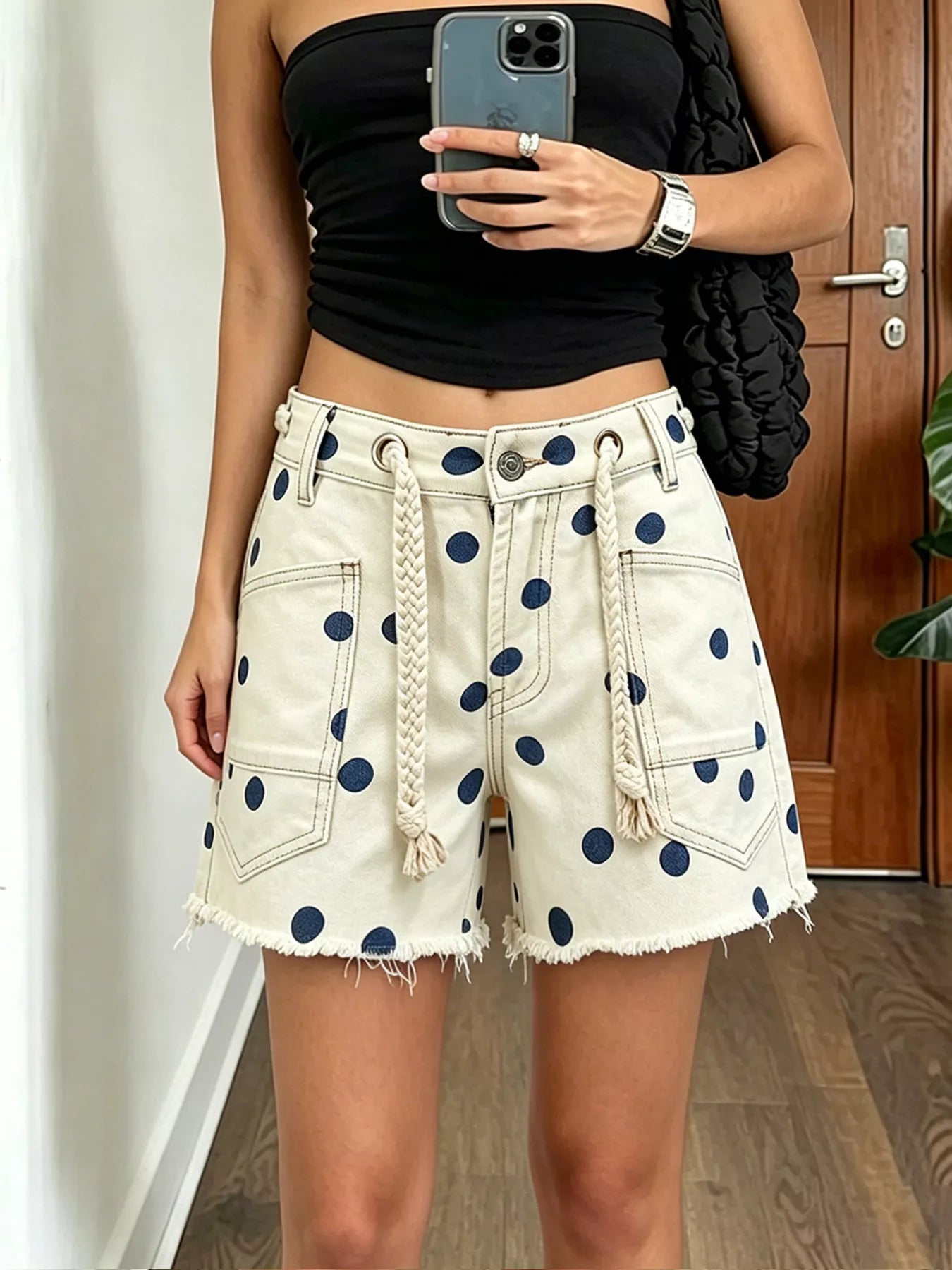 Polka dot denim shorts with braided drawstring, featuring raw hem and pockets, in peacock blue color.