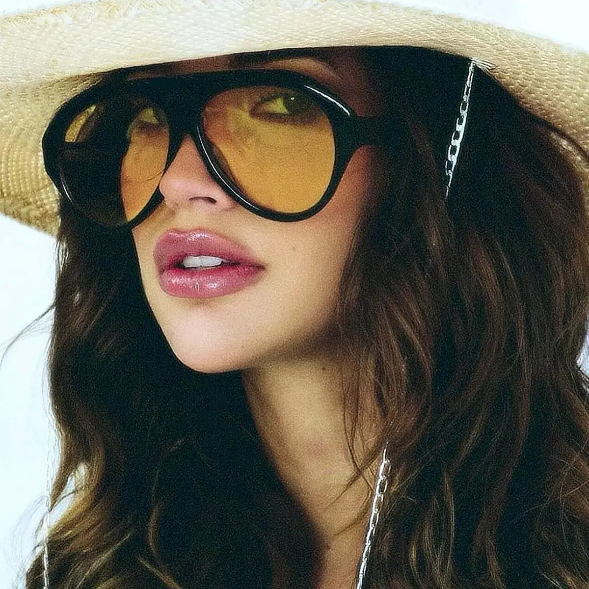 Vintage oversized aviator glasses with amber tinted lenses worn by a model in a straw hat.