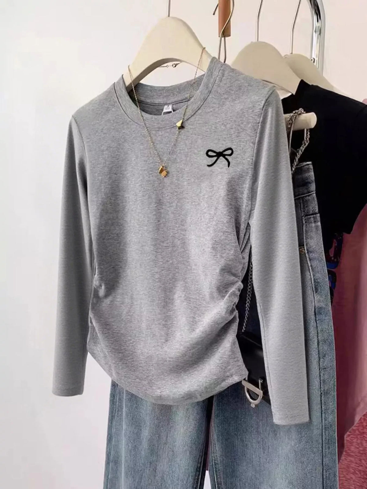 Cute Grey Bow Long Sleeve T-Shirt – Adorable Women’s Casual Top on a hanger with jeans and accessories.