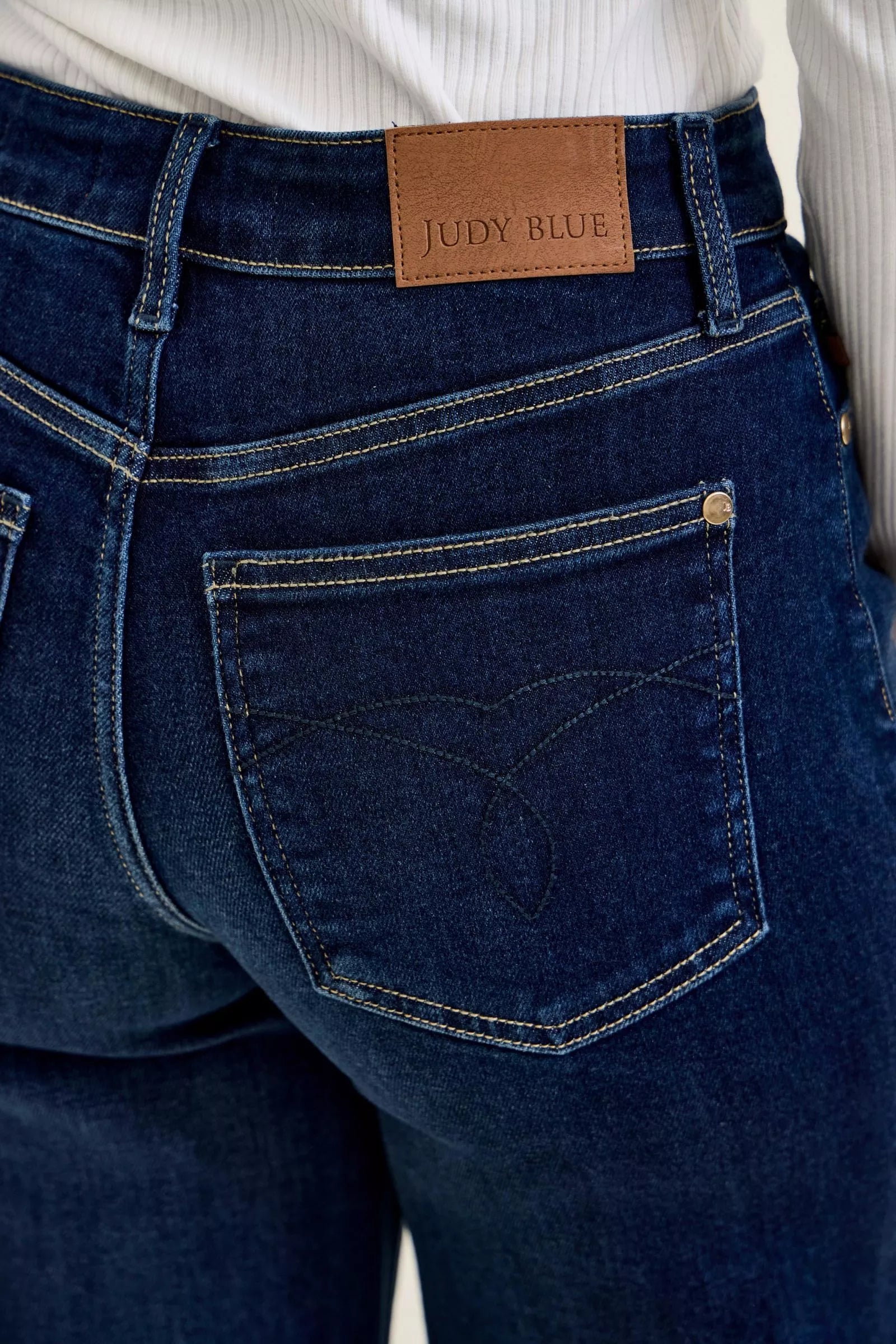 Close-up of dark blue high-waisted wide-leg jeans featuring back pocket and logo detail.